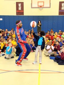 Zeus McClurkin, one of the stars of the Harlem Globetrotters, teaches a Milton Hershey School student how to spin a basketball on her fingertip.